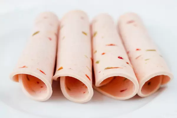 Close Up Photo of Rolled Ham Slices with Bell Pepper on White Background
