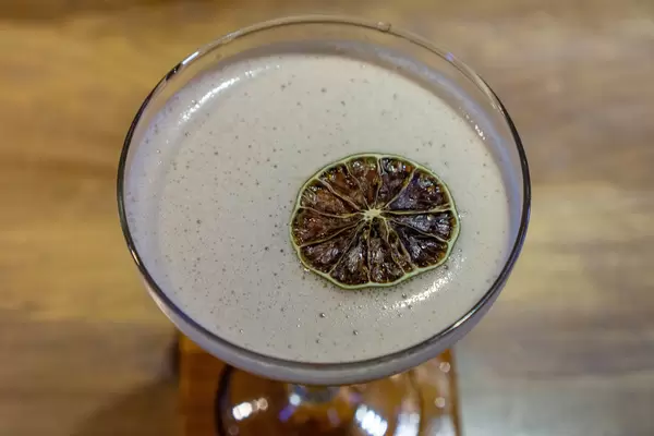 Close Up Photo of Strawberry Daiquiri Cocktail with Slice of Dried Orange on top on a Wooden Table