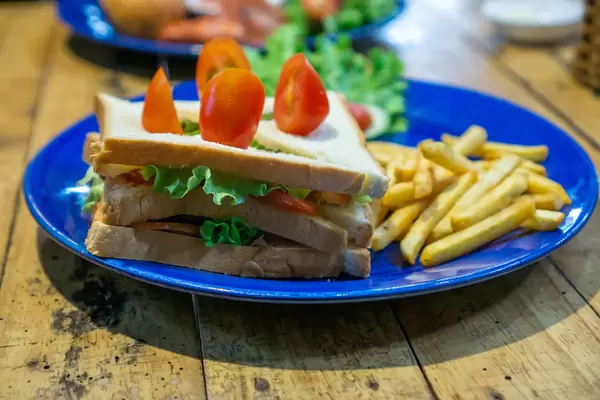 Close Up Photo of Tuna Sandwich with Lettuce and French Fries on Side on a Blue Plate