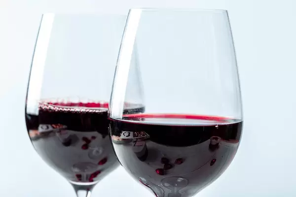 Close Up Photo of Two Wine Glasses half filled with Red Wine on White Background