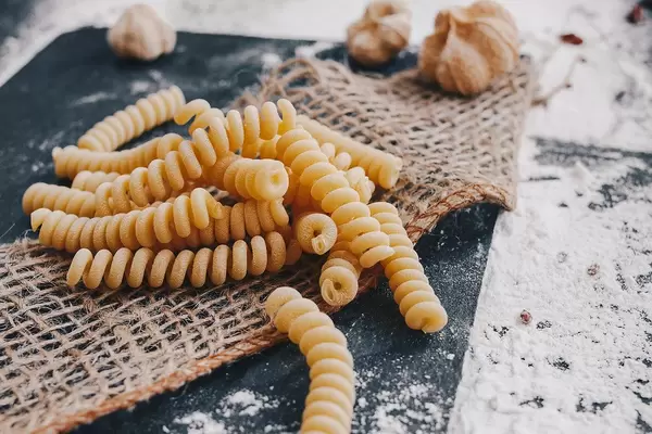 Close Up Photo of Uncooked Fusilli Pasta on a Table with Flour