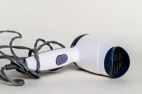 Close Up Photo of White Hair Dryer laying on a Table on White Background