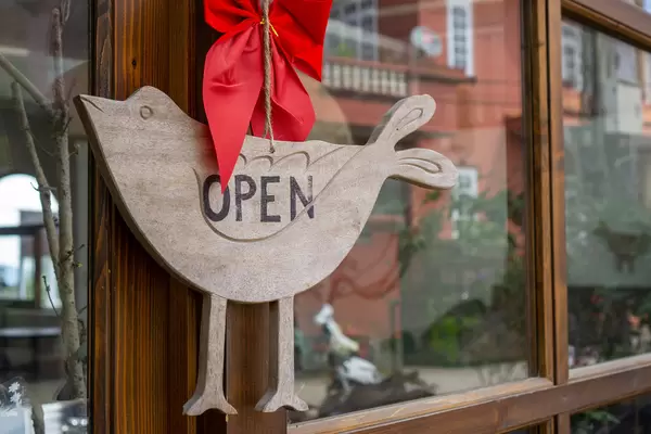 Close Up Photo of Wooden Open Sign Board in Bird Shape on a Door of a Cafe