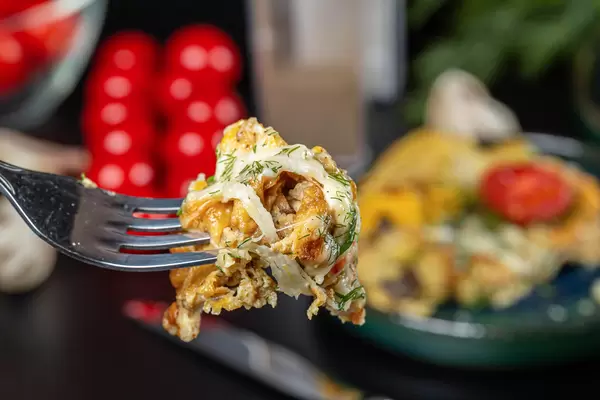 Close-up, piece of omelet with cheese and mushrooms on a fork