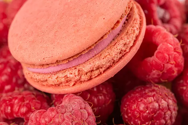 Close-up, pink macaroons on the background of raspberries
