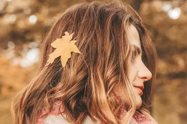 Close-up, portrait of a girl with a yellow leaf in her hair