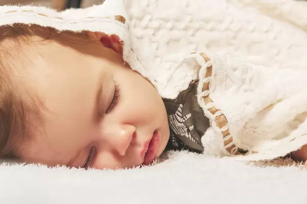 Close-up portrait of adorable baby boy sleeping in bed
