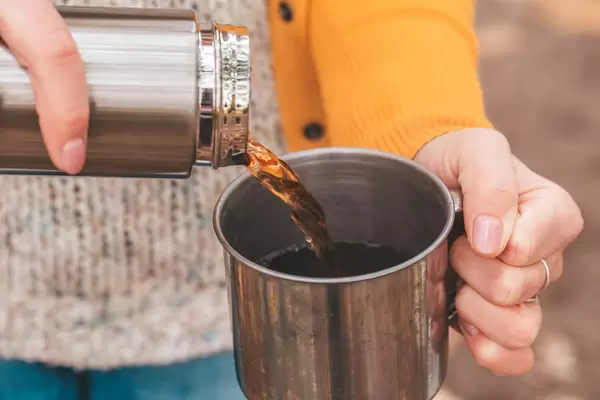 Close-up, pouring tea from a thermos into a mug
