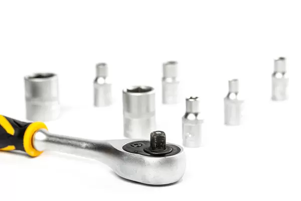 Close-up, ratchet wrench on white background with ratchet sockets behind