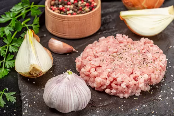 Close-up, raw minced meat with salt, vegetables and spices