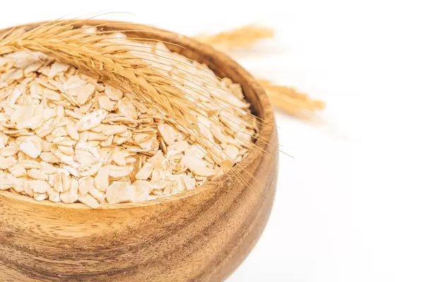 Close-up, raw oatmeal in a wooden bowl and spikelets