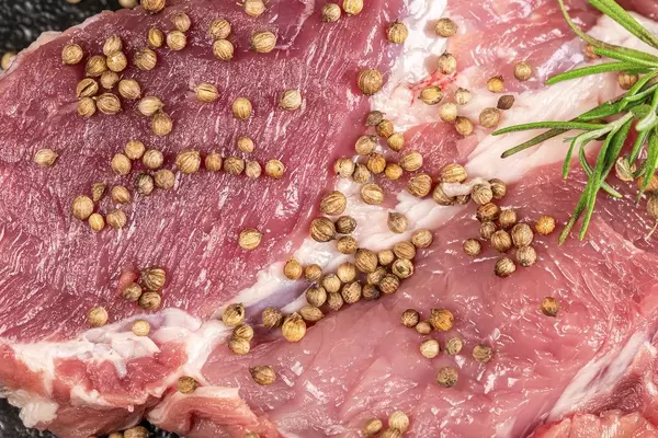 Close-up, raw pork steak with coriander and rosemary
