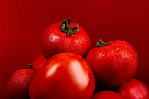 Close-up, ripe red tomatoes on a red background