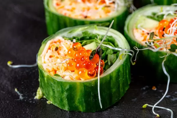 Close-up rolls with snow crab, avocado, cucumber and arugula on a black background (Flip 2019)
