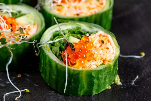 Close-up rolls with snow crab, avocado, cucumber and arugula on a black background