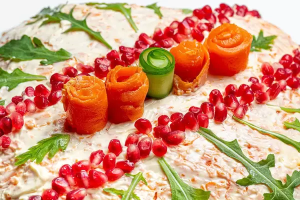 Close-up salad decorated with pomegranate seeds, arugula, carrot and cucumber