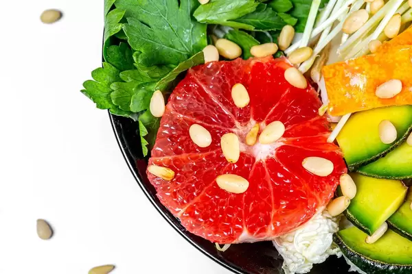 Close-up salad with grapefruit, avocado, micro greenery and pine nuts