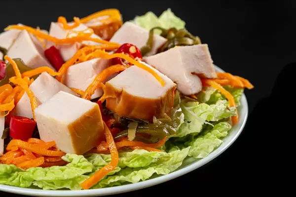 Close-up salad with smoked chicken, carrots, lettuce and seaweed
