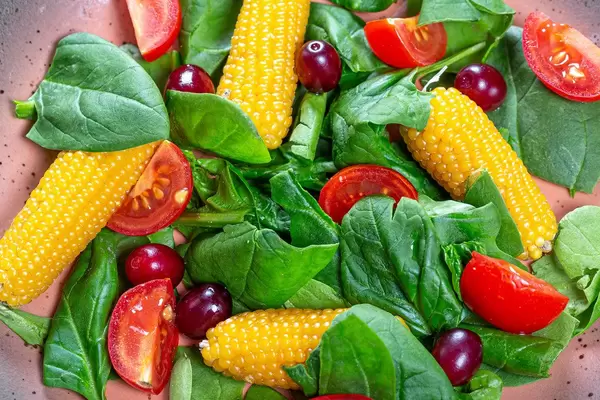 Close-up salad with spinach, tomatoes, corn and dogwood