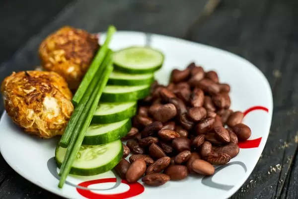 Close-up shot of oven-baked chicken meat cutlets, cucumber slices and boiled kidney bean with scallions