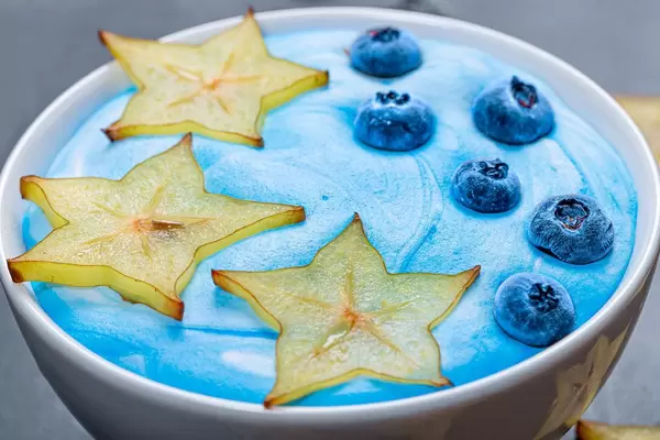 Close up slices of fresh ripe carambola and blueberry berries with blue yogurt on oatmeal (Flip 2019)