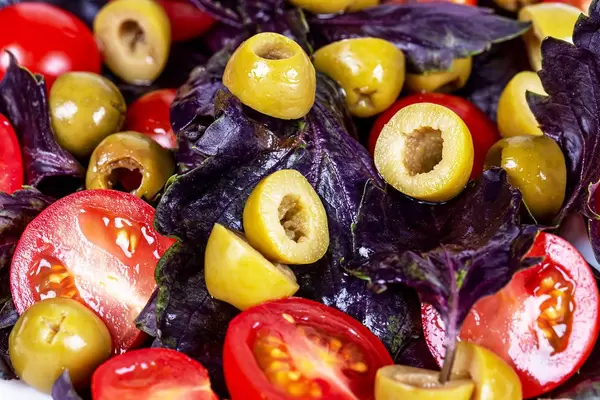 Close-up, slices of tomatoes, pickled green olives and basil leaves