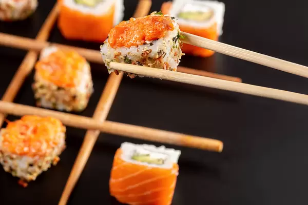 Close-up, spicy roll with tobiko caviar in chopsticks