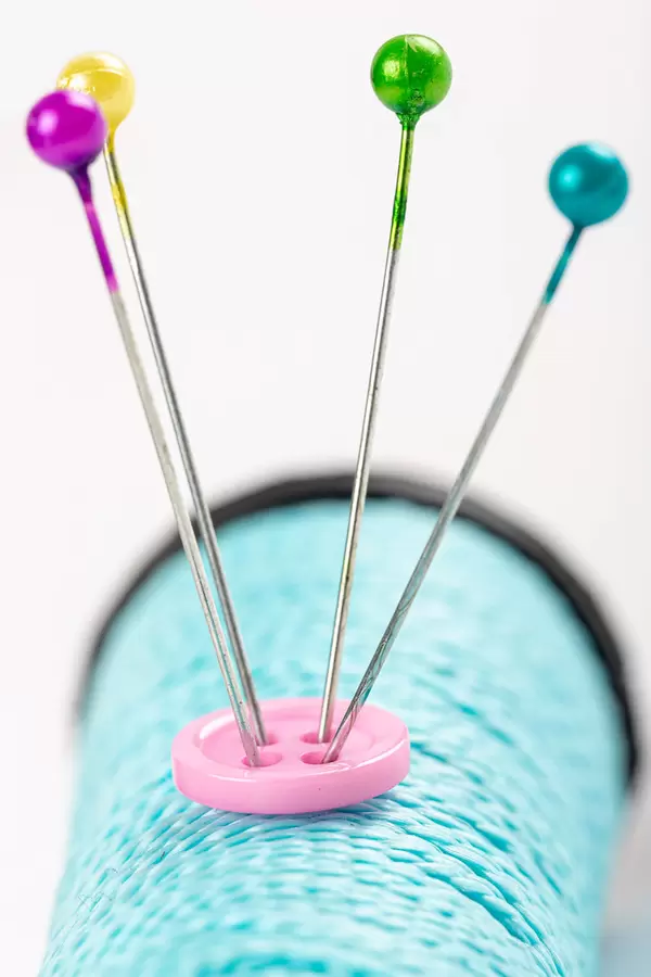 Close-up, spool of blue thread, button and sewing pins