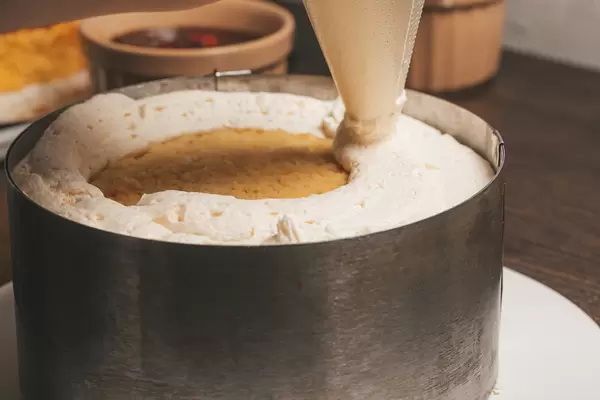 Close-up squeezing cream out of a pastry bag onto a biscuit