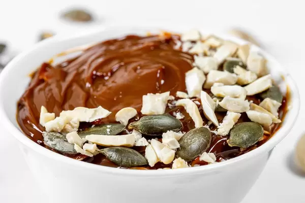 Close-up sweet dessert with condensed milk, cashews and pumpkin seeds (Flip 2019)