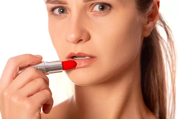 Close-up, the girl paints her lips with red lipstick