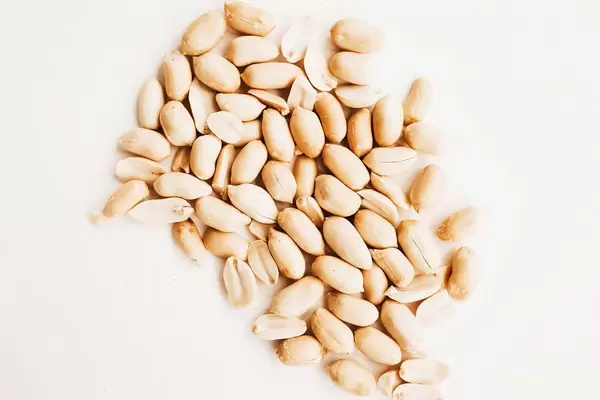 Close up top view of raw peanuts on white background