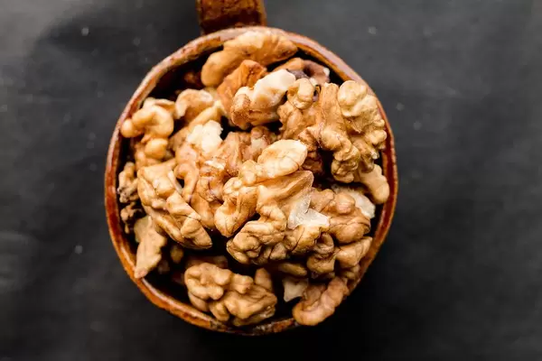 Close Up Top View Photo of Walnuts in a Ceramic Cup on Dark Background