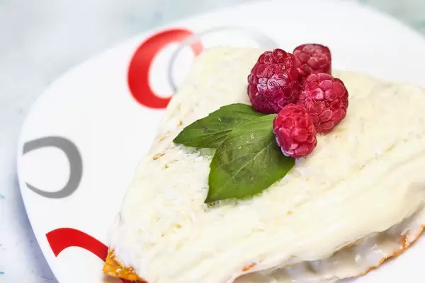 Close-up view of carrot cake with cream and fresh raspberries on it