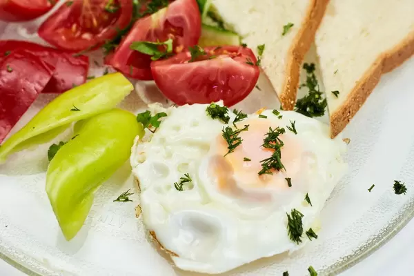 Close-up view of fried egg with fresh vegetables and toast