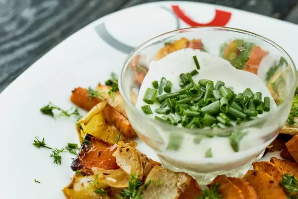 Close-up view of yummy sauce with green onions and vegetable fries on the plate