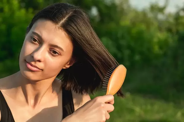 Close-up, woman brushing her hair on nature background