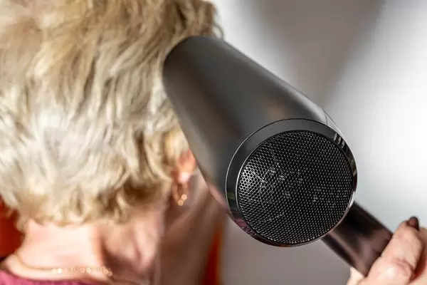 Close up, woman dries hair black hairdryer