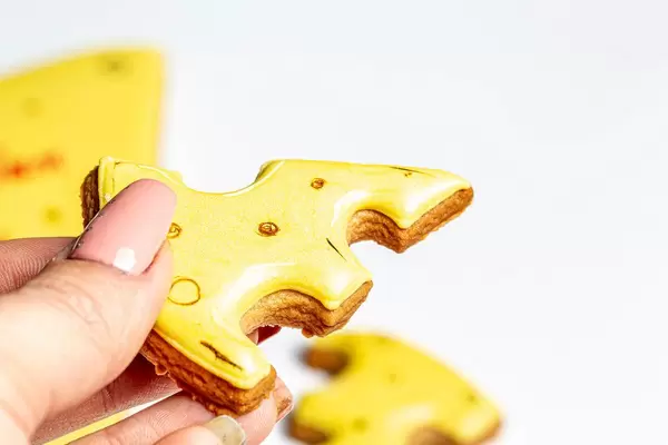 Closeup gingerbread in the shape of slices of cheese in hand