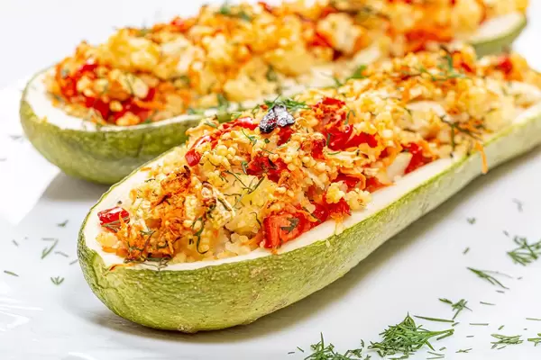Closeup of baked zucchini halves with vegetables and couscous