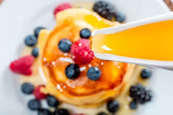 Closeup of honey pouring on the pancakes with berries (Flip 2019)