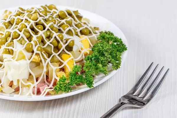 Closeup of Olivier salad with fork on white wooden table (Flip 2019)