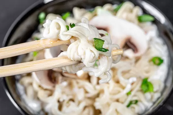 Closeup of pasta with cheese and onion greens on chopsticks (Flip 2019)
