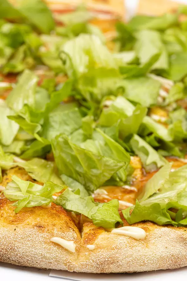 Closeup of Pizza with green lettuce salad on the top