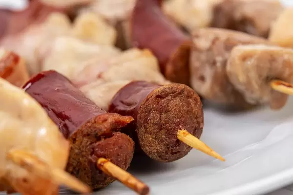 Closeup of sliced Sausage Bacon and Meat on the wooden grill stick (Flip 2019)