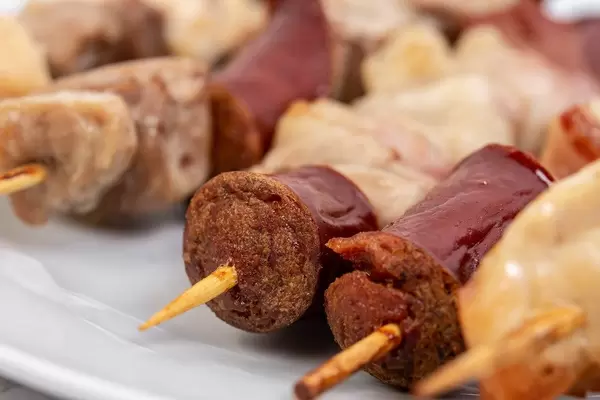 Closeup of sliced Sausage Bacon and Meat on the wooden grill stick