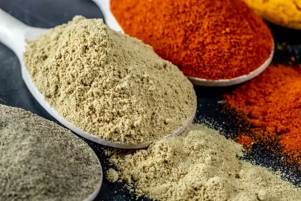 Closeup of turmeric, pepper and ground ginger in a wooden spoon