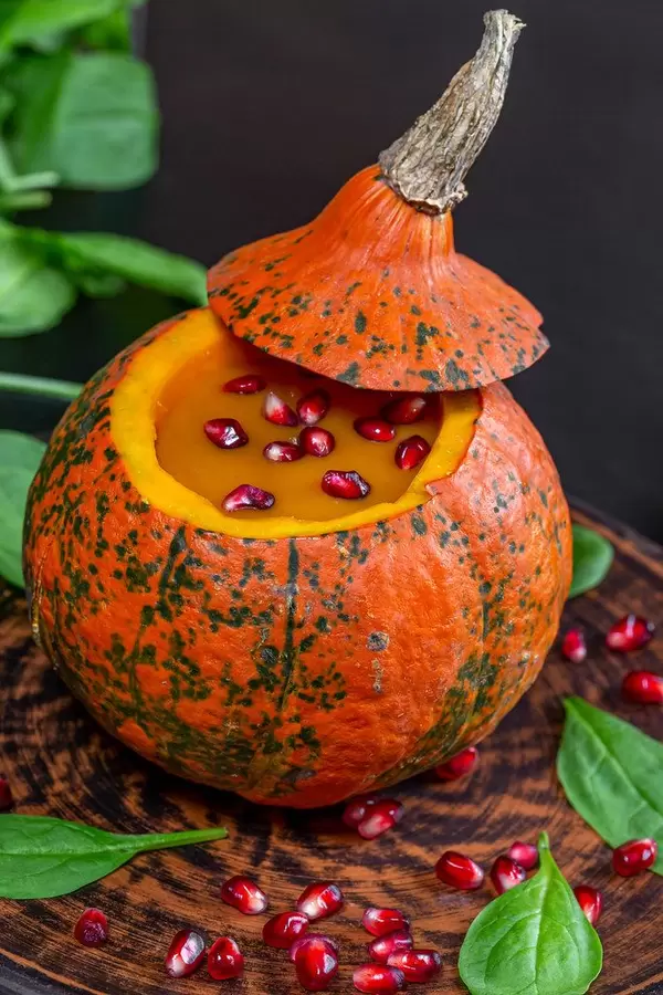 Closeup of yummy pumpkin Halloween with pomegranate in fresh spinach leaves
