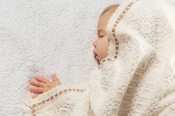 Closeup portrait of sleeping baby covered with knitted blanket