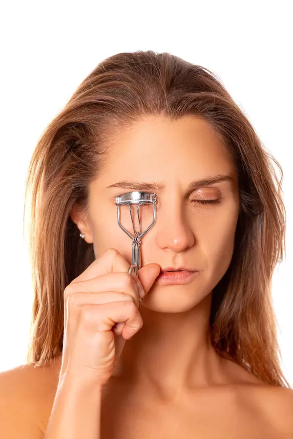 Closeup young beautiful woman making curl eyelashes